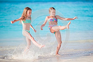 Little happy kids have a lot of fun at tropical beach playing together at shallow water.
