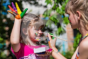 Little happy sisters play with colors in the park, children play, children paint each other