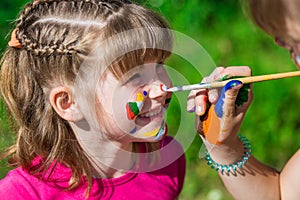 Little happy sisters play with colors in the park, children play, children paint each other