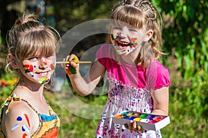 Little happy sisters play with colors in the park, children play, children paint each other