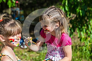 Little happy sisters play with colors in the park, children play, children paint each other