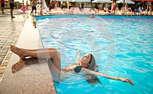 Little happy teenage girl swims in the pool