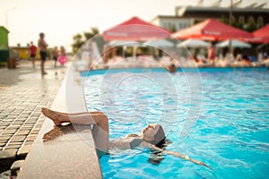 Little happy teenage girl swims in the pool