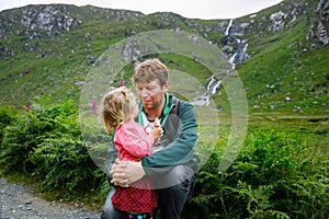 Little happy toddler girl hugging with father in Glenveagh national park in Ireland. Smiling and laughing baby child and
