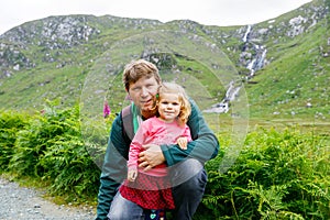 Little happy toddler girl hugging with father in Glenveagh national park in Ireland. Smiling and laughing baby child and