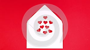 Little hearts come out of white envelope on red theme. Stop motion