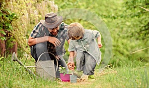 Little helper in garden. Planting flowers. Make planet greener. Growing plants. Take care of plants. Boy and father in