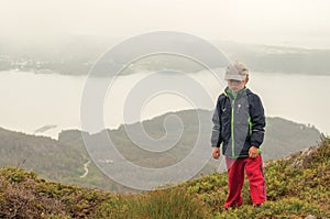 A little hiker standing on the top of the hill over background o