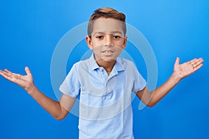 Little hispanic boy wearing casual blue t shirt shouting and screaming loud to side with hand on mouth