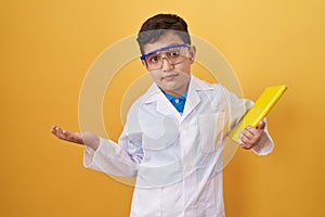 Little hispanic boy wearing scientist glasses celebrating achievement with happy smile and winner expression with raised hand