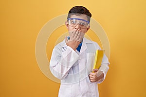 Little hispanic boy wearing scientist glasses covering mouth with hand, shocked and afraid for mistake