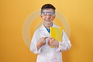 Little hispanic boy wearing scientist glasses smiling happy pointing with hand and finger