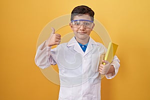 Little hispanic boy wearing scientist glasses smiling happy and positive, thumb up doing excellent and approval sign