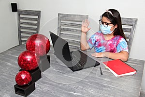 Little Hispanic girl doing school at home with glasses and face masks due to the quarantine of the Covid-19 pandemic due to corona
