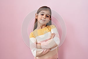 Little hispanic girl wearing sweater over pink background happy face smiling with crossed arms looking at the camera