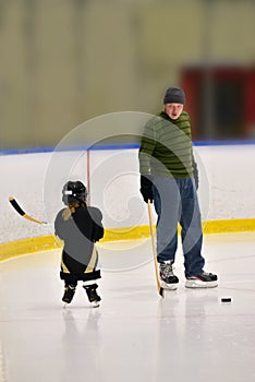 Little hockey girl is wearing in full equipment: helmet, glows, skates, stick. She is hold