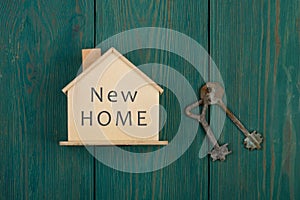 little house with text & x22;new home& x22; and key on blue wooden desk photo