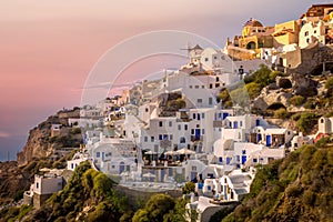 Little houses in the cliff at the city of Oia in Santorini, Greece. .Pink skies fills the sky