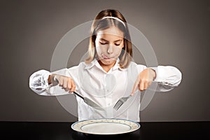 Little hungry girl sitting at table