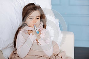 Little ill girl measuring temperature