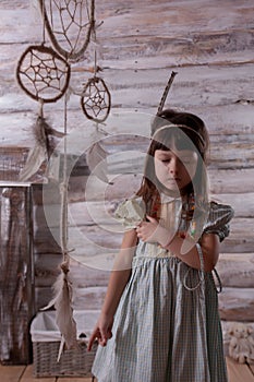 Little indian girl feathers in her hands. dreamcatcher. wooden background