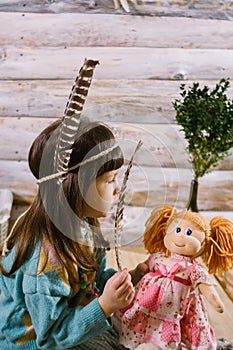 Little indian girl holding a doll and feathers in her hands