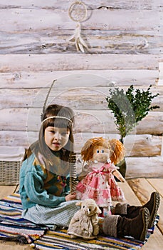 Little indian girl holding a doll and feathers in her hands. dreamcatcher. wooden background