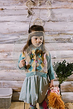 Little indian girl holding a doll and feathers in her hands. dreamcatcher. wooden background