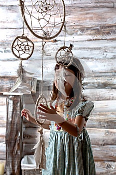 Little indian girl holding dreamcatcher in her hands. wooden background