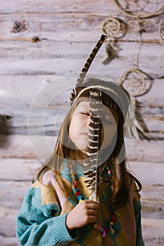 Little indian girl holding  feathers in her hands. dreamcatcher. wooden background