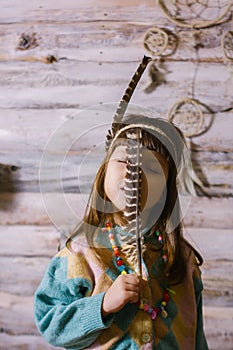 Little indian girl holding feathers in her hands. dreamcatcher. wooden background