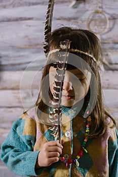 Little indian girl holding feathers in her hands. dreamcatcher. wooden background