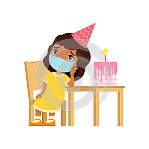 Little indian girl is sad on her birthday. Cute kid with a medical mask on his face sits on a chair.