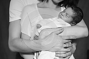 Little infant baby boy sleeping laying on mothers arms. Mother k