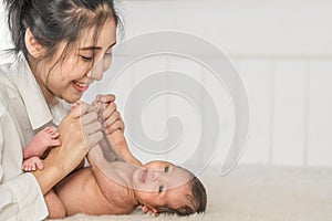 Little infant baby lying on bed with happy face mother holding hand