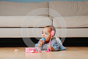 Little infant baby playing on the floor, eating doll head