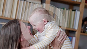 Little infant child laughing having fun and looking in camera. Happy Cheerful Family. Mother And Baby Kissing.