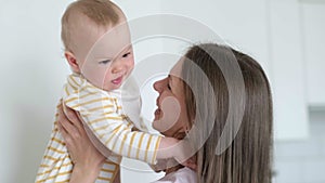 Little infant child laughing having fun and looking in camera. Happy Cheerful Family. Mother And Baby Kissing.