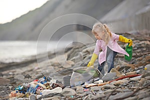 Little janitor picking up garbage at the beach