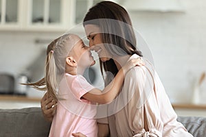 Little joyful kid girl touching noses with happy young mommy.