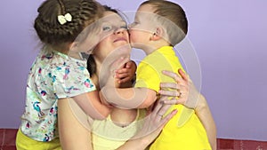 Little joyful kids hugging and kissing happy mother.