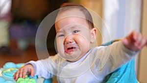 Little kazakh girl standing at home walker and crying unhappy baby