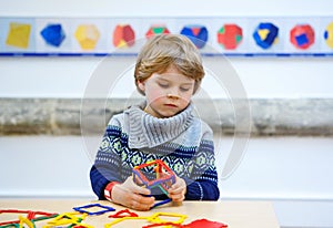 Little kid boy building geometric figures with plastic blocks