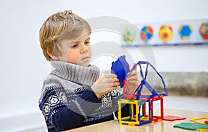 Little kid boy building geometric figures with plastic blocks