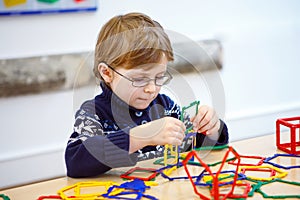 Little kid boy building geometric figures with plastic blocks