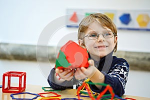 Little kid boy building geometric figures with plastic blocks