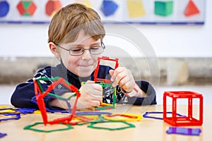 Little kid boy building geometric figures with plastic blocks