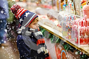 Little kid boy with candy cane stand on Christmas