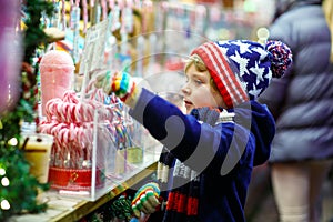 Little kid boy with candy cane stand on Christmas market