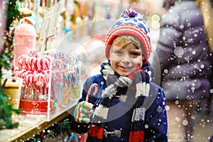 Little kid boy with candy cane stand on Christmas market